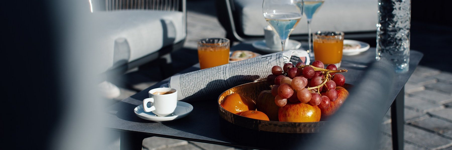 Tisch auf einer Terrasse mit Kaffee, Orangensaft, Champagner und einem Obstteller