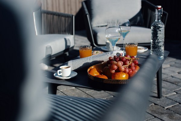 Tisch auf einer Terrasse mit Kaffee, Orangensaft, Champagner und einem Obstteller