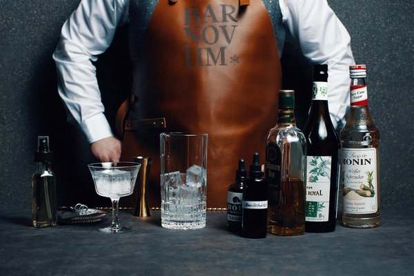 Bartender von der Bar Novum des Panoramahotel Alpenstern mit Spirituosen und Cocktailglas