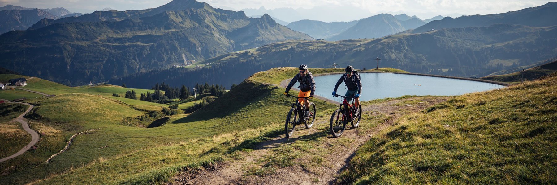 Fahrradfahrer beim Mountainbiken in den Bergen im Sommer mit Wolken am Himmel