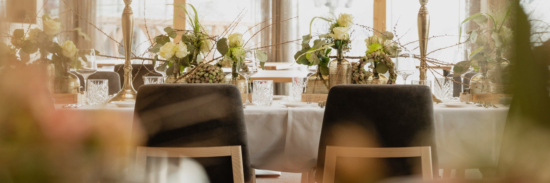 Gedeckter Tisch mit Tischschmuck für Hochzeit mit Kerzenleuchtern, weißen Rosen und grünen Blumen