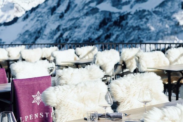 Tische und Stühle mit Fell auf der Terrasse des Panoramarestaurants Alpenstern im Winter