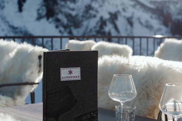 Speisekarte auf einem Tisch des Panoramarestaurants Alpenstern mit Blick auf die verschneiten Berge