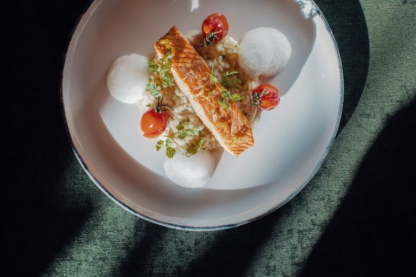 Modern angerichtetes Gericht mit Lachs auf Risotto, Tomaten und Schaum