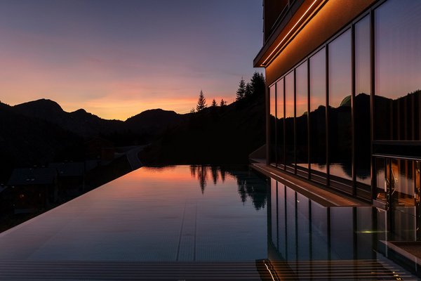 Spiegelnder Outdoor Infinity Pool vor einer Bergsilhouette bei Dämmerung