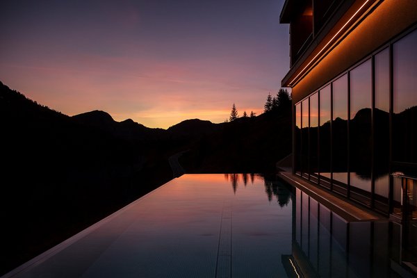 Spiegelnder Outdoor Infinity Pool vor einer Bergsilhouette bei Dämmerung