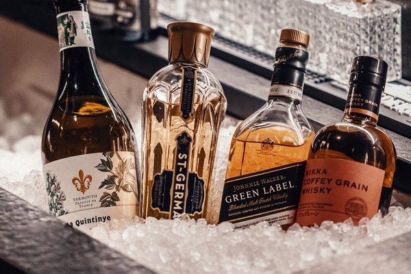 Whiskey und Likörflaschen liegen im Crushed Ice an der Bar mit Cocktail Bitters