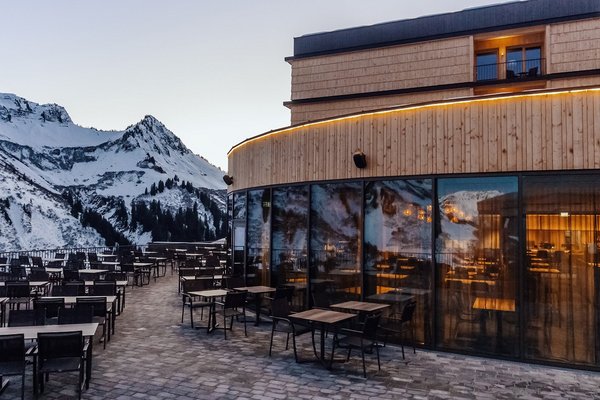 Terrasse und Glasfassade des Panoramarestaurants Alpenstern mit Blick auf die verschneiten Berge