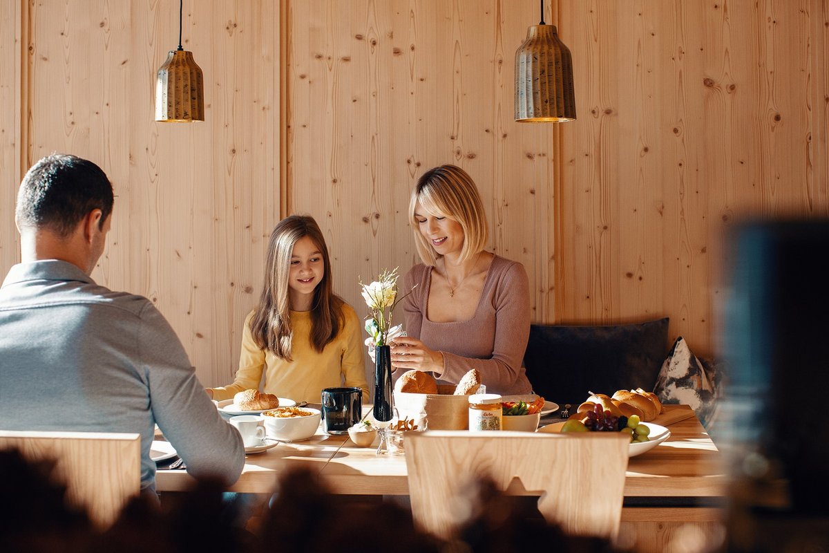 Familie mit Kind sitzt in einer modernen Stube aus Holz beim Frühstück