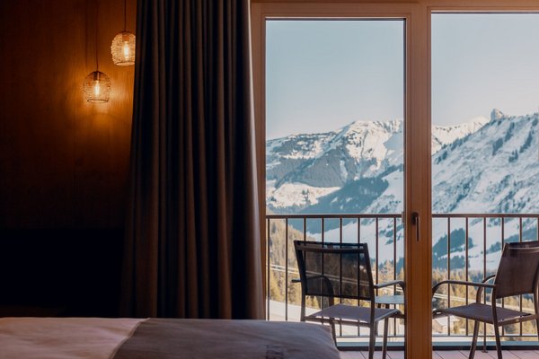 Doppelzimmer mit Balkon und Balkonmöbel mit Blick auf das verschneite Bergpanorama