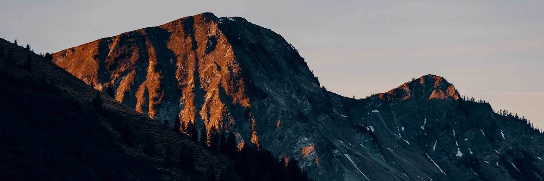 Teilweise mit Schnee bedeckter Bergkamm bei Dämmerung