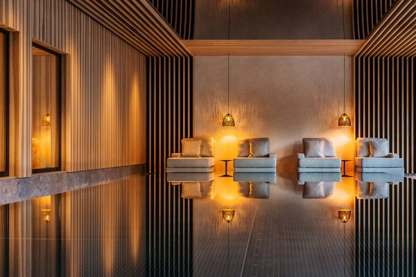 Spiegelnder Infinity Pool und Kuschelliegen in einem Wellnessbereich mit Spiegeldecke